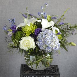 White lilies, roses, and lavender hydrangea in a glass vase
