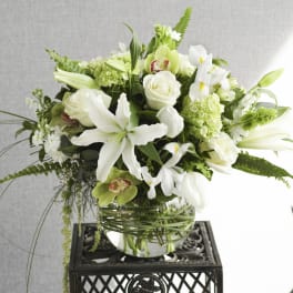 White and green floral arrangement in a glass bowl vase