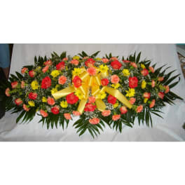 Oval floral spray with red roses, yellow daisies, and a gold ribbon bow