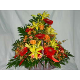 Basket arrangement with yellow lilies, red gerberas, and orange roses