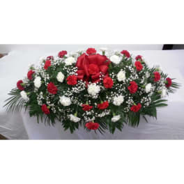 Red and white carnation funeral spray with a red ribbon