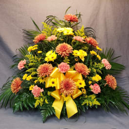 Large floral spray with yellow and peach flowers and a yellow ribbon