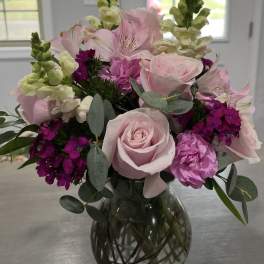 Pink roses and mixed blooms arranged in a glass vase