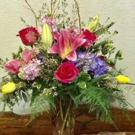 Mixed bouquet with pink lilies, roses, and purple hydrangeas in a glass vase