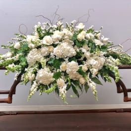 Large white floral arrangement with roses and hydrangeas on a wooden table