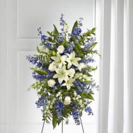Tall standing spray of white lilies, white roses, and blue flowers