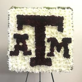 Square floral tribute with maroon letters on a white flower background