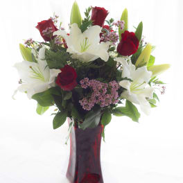 Red roses and white lilies arranged in a red glass vase