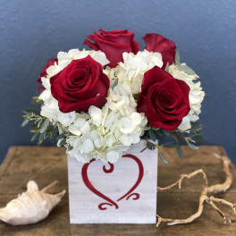 Red roses and white hydrangeas in a white box with a heart design