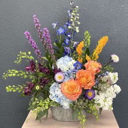 Colorful mixed flower arrangement in a textured gray container