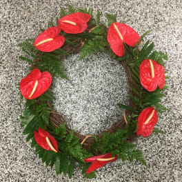 Red floral wreath with green foliage on a speckled gray surface