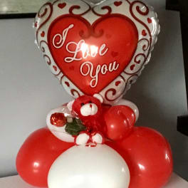 Heart-shaped "I Love You" balloon with red and white balloons and a teddy bear