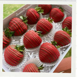 Box of chocolate-covered strawberries with red drizzle
