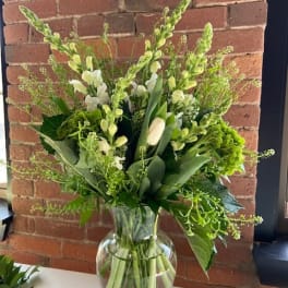 Green and white floral arrangement in a clear glass vase