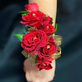 Red rose wrist corsage with gold ribbon on a wrist