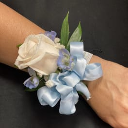White rose wrist corsage with pale blue ribbon and small blue flowers
