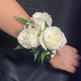 White rose wrist corsage with green leaves