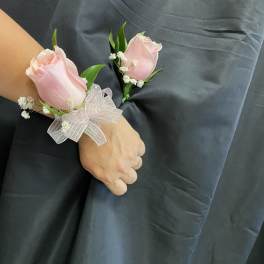 Two pink rose corsages with white baby's breath and ribbon