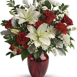 Red roses and white lilies in a red glass vase