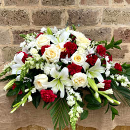 Red and white funeral spray with lilies, roses, carnations, and snapdragons in an elongated design