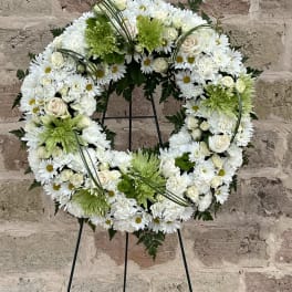 White and green floral wreath on a black stand