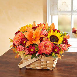 Basket arrangement of orange lilies, roses, sunflowers, and mums