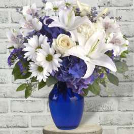 White lilies and daisies in a blue glass vase