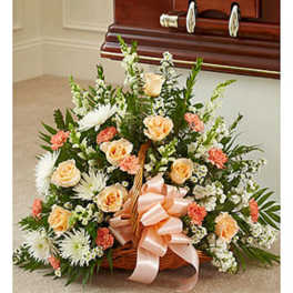 Basket arrangement of peach and white flowers with a pink ribbon
