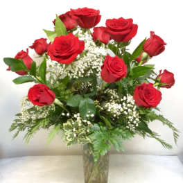 Red roses arranged in a clear glass vase with white filler flowers