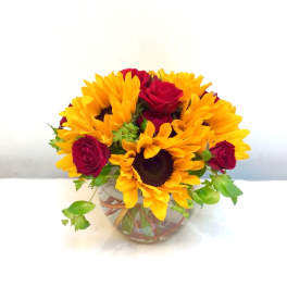 Bouquet of yellow sunflowers and red roses in a clear glass vase