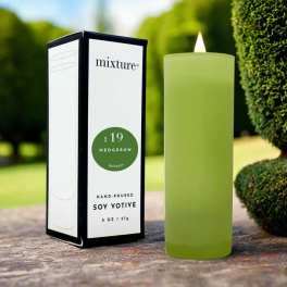 Green votive candle beside its boxed packaging