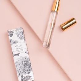 Perfume spray bottle with gold cap and matching box on a pink background