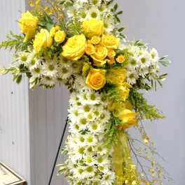 Yellow roses and white daisies arranged in a cross-shaped floral tribute