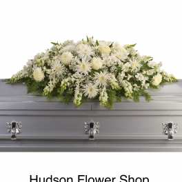 White floral casket spray on a gray coffin
