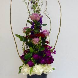 Tall floral arrangement with pink and red roses in a black vase