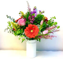 Mixed bouquet with a red gerbera daisy and pink roses in a white vase