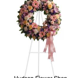 Pastel floral wreath on a white easel with pink ribbon