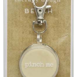 Packaged keychain with a round cream charm and metal clip