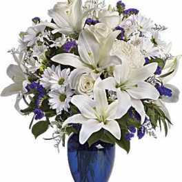 White lilies and daisies in a blue glass vase