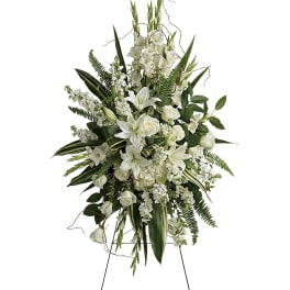 White floral standing spray with lilies and roses on a metal easel