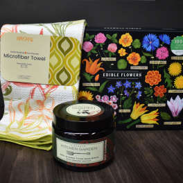 Gift set with a floral kitchen towel, edible flowers puzzle, and hand scrub jar