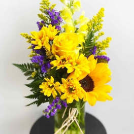 Bouquet of yellow sunflowers and roses in a glass vase