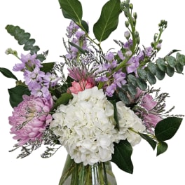 Bouquet of white hydrangea, pink chrysanthemums, and lavender flowers in a glass vase