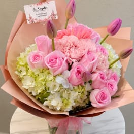 Pink roses and carnations with tulip buds in peach wrapping