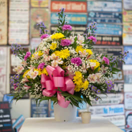 Mixed bouquet in a white container with a pink ribbon