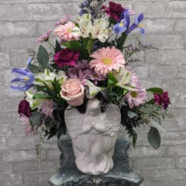 Mixed bouquet in a white angel vase with pink, white, purple, and blue flowers