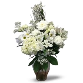 White floral arrangement in a glass vase with daisies and hydrangeas