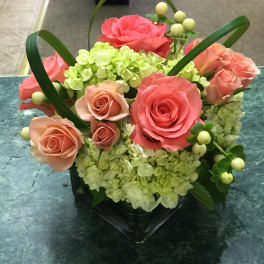 Pink roses and green hydrangeas arranged in a black vase