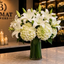 White lilies and pale hydrangeas in a glass vase