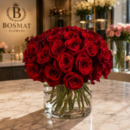 Red rose bouquet in a clear glass vase on a marble counter